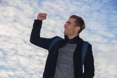 Beyaz Genç Eller yukarıda ile mavi gözlü sarışın adam ve mavi gökyüzü arka plan bulutlar ile. 