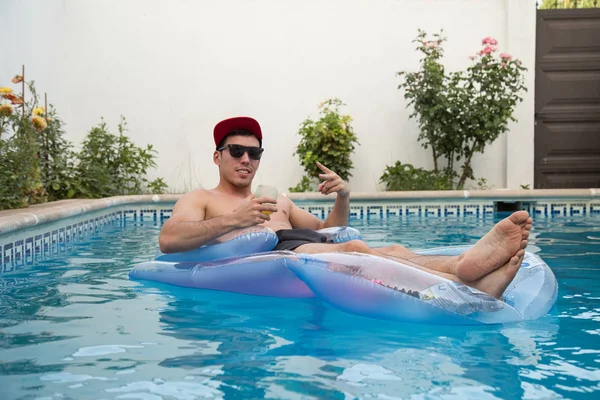 Jeune homme fort buvant de la bière sur un lit d'air dans la piscine — Photo