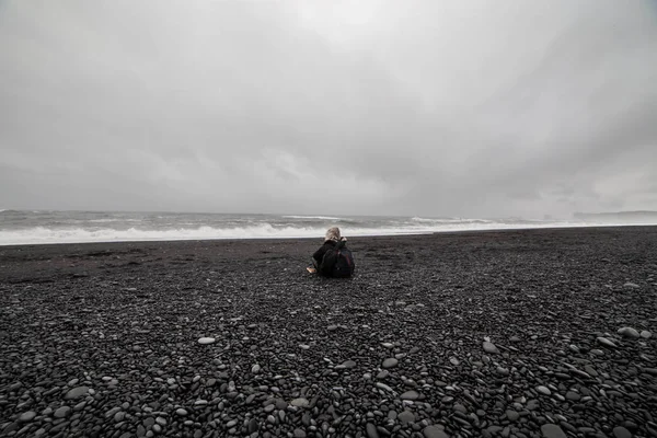 Siyah Kum Plajı üzerinde oturan genç bir kadın arkadan görünüm