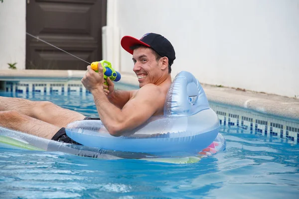 Χαρούμενος άνθρωπος με όπλο του νερού στην πισίνα — Φωτογραφία Αρχείου