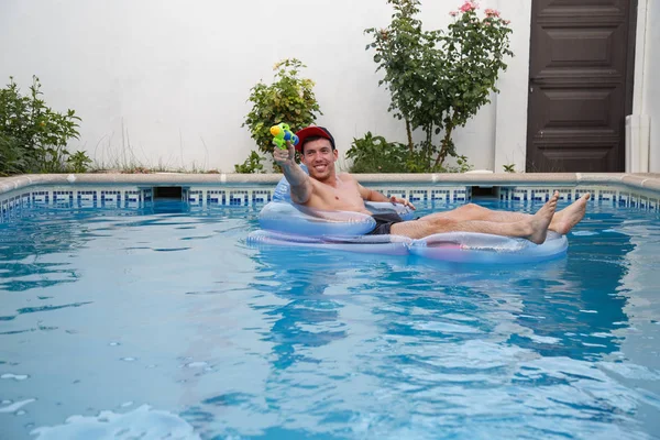 Homme joyeux avec pistolet à eau dans la piscine — Photo