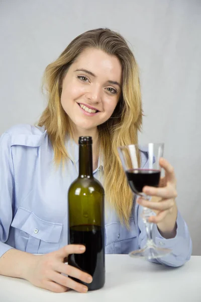 年轻的女人在白色的背景上喝上一杯红酒 — 图库照片