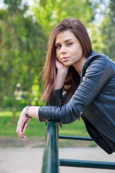 Young Woman Black Leather Jacket Holding Smartphone Leaning Fence Looking — Stock Photo, Image