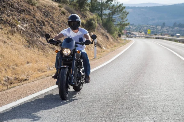 Genç adam dağlarda yolda güneşli bir günde bir motosiklet sürme. 