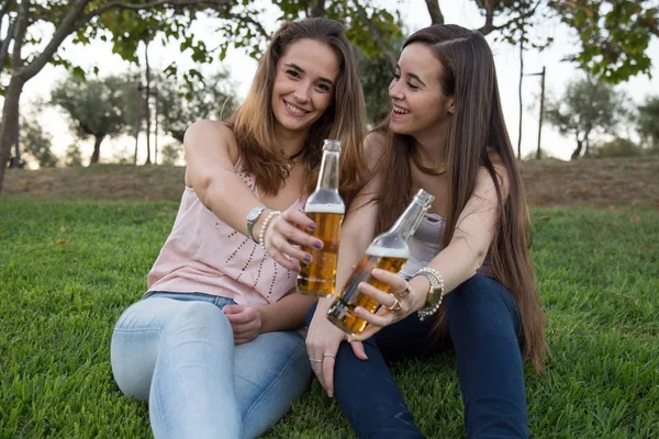 Dos Jóvenes Mujeres Riendo Posando Césped Parque Brindando Con Botellas — Foto de Stock