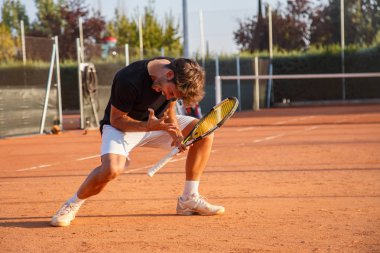 Tenis Kortu etkileyici görünümlü parlak güneş ışığı altında üzerinde zafer kutluyor raket ile sportif adam heyecanlı.  