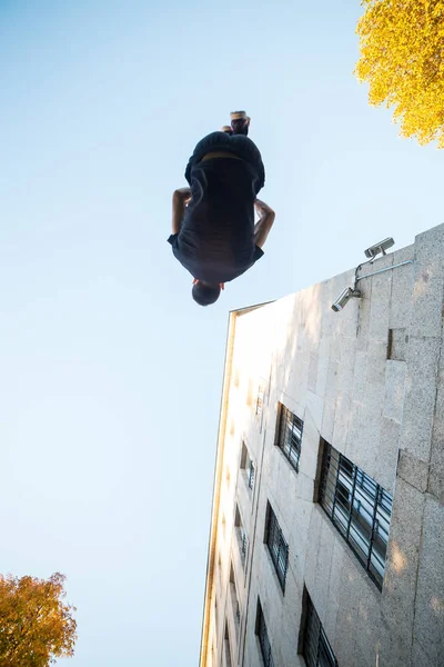 Young man doing a side flip or somersault while practicing parkour on the street.