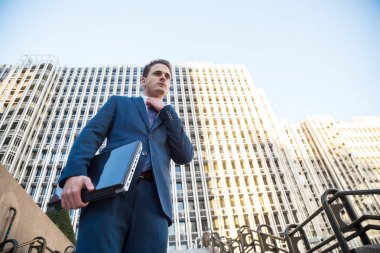 Elini uzak seyir içinde belgili tanımlık laptop ile poz şık elbiseli genç adam.