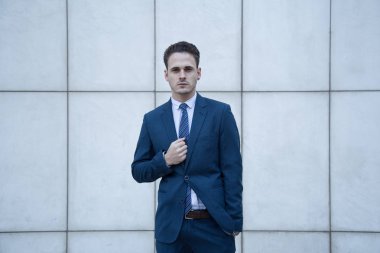 Satır bir bina ile beyaz bir arka plan üzerinde takım elbise giymiş genç iş adamı.