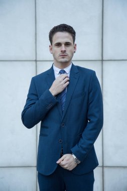 Satır bir bina ile beyaz bir arka plan üzerinde takım elbise giymiş genç iş adamı.