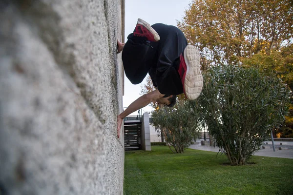 Young man doing an amazing parkour trick by making a turn on a wall in the street.