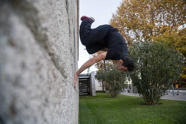 Young man doing an amazing parkour trick by making a turn on a wall in the street.