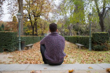 Sonbahar Park merdivenlerde oturan ve uzağa bakarak düşünceli genç adam. 