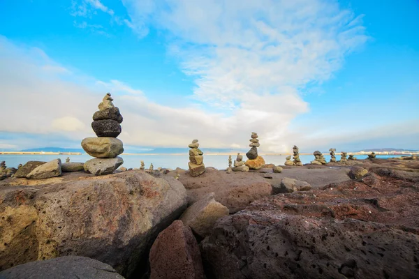 Series of stacked rock columns called cairns facing the sea in Reykjavik, Iceland.