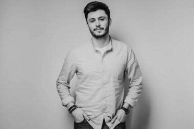 Gri arka planda kameraya poz veren yakışıklı bir adamın siyah beyaz portresi.
