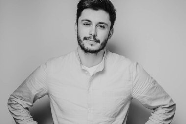 Gri arka planda kameraya poz veren yakışıklı bir adamın siyah beyaz portresi.