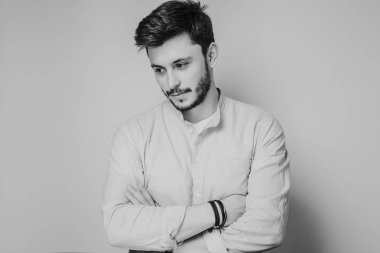 Gri arka planda kameraya poz veren yakışıklı bir adamın siyah beyaz portresi.