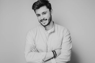 Gri arka planda kameraya poz veren yakışıklı bir adamın siyah beyaz portresi.