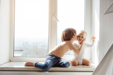 İki küçük kardeş pencere kenarında birlikte vakit geçiriyorlar. Büyük kardeş ufaklığa bir kitap okur. Gerçek çocuk arkadaşlığı. Dans eden çocuklar. Çocuklar sarılır ve öper.