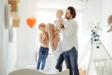 Güneşli bir odada dört aile üyesi iki tatlı çocukla birlikte oynuyor. Karantina sırasında evdeki güneşli günlerin tadını çıkarıyorum. Mükemmel ebeveynlik ilişkisi. Birlikte evde kalalım. Aile zamanı.