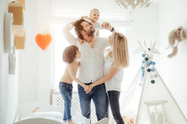 Güneşli bir odada dört aile üyesi iki tatlı çocukla birlikte oynuyor. Karantina sırasında evdeki güneşli günlerin tadını çıkarıyorum. Mükemmel ebeveynlik ilişkisi. Birlikte evde kalalım. Aile zamanı.