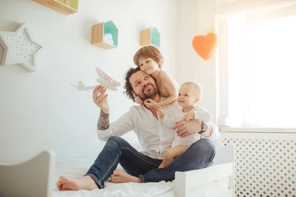 Oyuncak bir uçakla oynayan iki oğlu olan genç bir baba. Mutlu bir aile, güneşli bir odada birlikte zaman geçiren üç çocuk. Büyük kardeş babayı kucaklıyor.