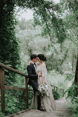 Gülümseyen gelin ve damat birlikte vakit geçiriyorlar. Dağ tepelerinde poz vermek. Beyaz elbiseli güzel sarışın beyaz gelin ve yakışıklı damat. Sarıl, öp ve arkadaşlığın tadını çıkar.