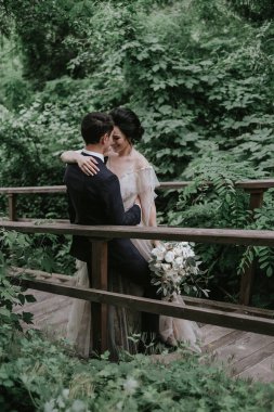 Gülümseyen gelin ve damat birlikte vakit geçiriyorlar. Dağ tepelerinde poz vermek. Beyaz elbiseli güzel sarışın beyaz gelin ve yakışıklı damat. Sarıl, öp ve arkadaşlığın tadını çıkar.