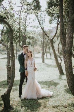 Güzel bir gelin ve damadın portresi kucaklaşır, öpüşür ve kucaklaşır. Doğanın bağrında aşık bir çift. Yakışıklı damat ve ormanda poz veren güzel sarışın gelin. Modern elbise ve takım elbise