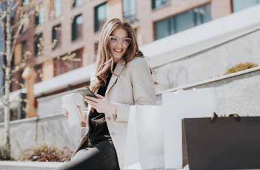 Alışveriş torbaları ve akıllı telefonları olan çekici bir kız. Arka planda modern şehir megapolis 'i var. İnternetten sipariş veren ve alışveriş yapan bir bayan. Güzel beyaz kadın.