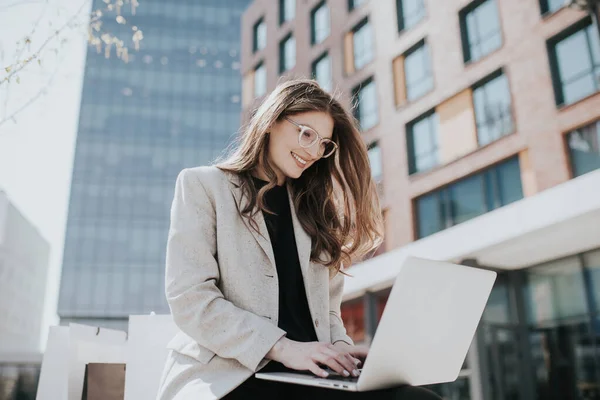 Beautiful lady with laptop and shopping bags, making online orders. Female influencer chat with her friends. Cute smiling teen typing on computer keyboard.