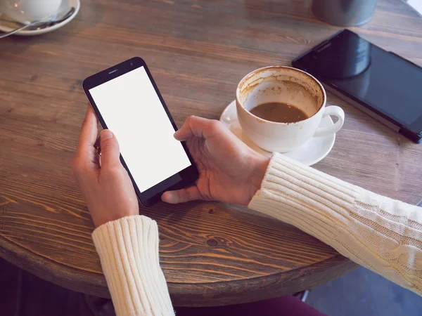 Kadın için bir ahşap bir kafede oturup telefon haberlerde okur