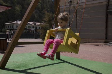 sevimli kız mutlu çocuk parkında salıncağa eğleniyor. Güneşli bahar günü