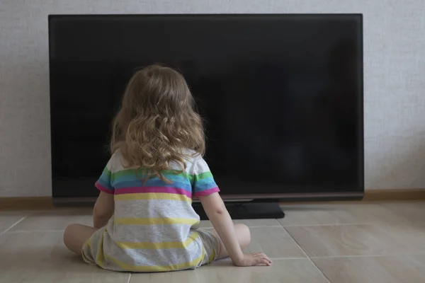Kavramsal portre. Yerde döşeme ve evde Tv izlerken küçük kız