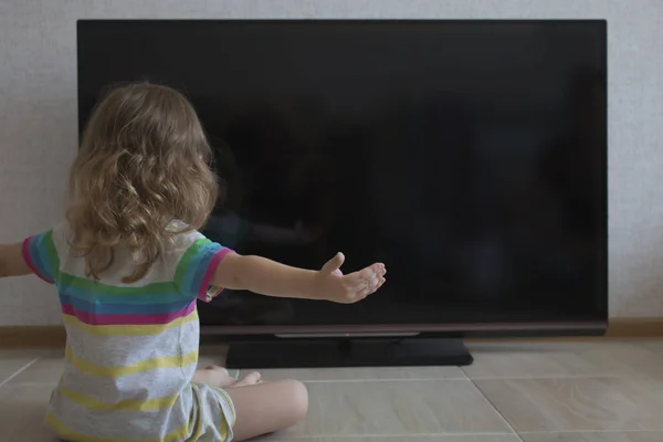 Kavramsal portre. Küçük kız kız kollarını siyah bir Tv ekran arka taraf oturur yaymak