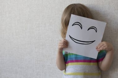 Kavramsal portre smiley. Küçük bir çocuğun yüzünü komik maskesi kapsar. gülen yüz.