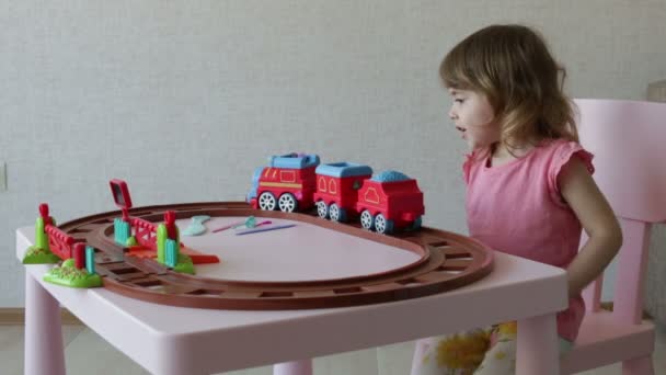 Девочка играла с игрушечными поездами на рельсах — стоковое видео