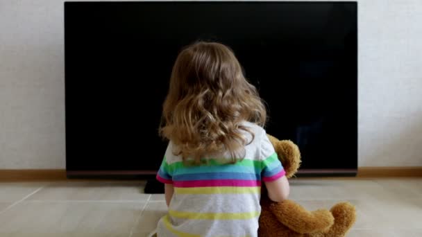 概念的肖像。小女孩正坐在反对黑屏了电视机的地板上 — 图库视频影像