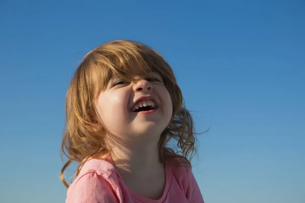 Śmiejąc się mała dziewczynka na tle nieba — Zdjęcie stockowe