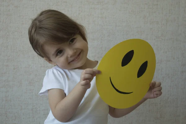 Un niño sosteniendo un círculo amarillo con cara de sonrisa emoticono en lugar de cabeza . — Foto de Stock