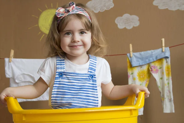 La niña está lavando la ropa y colgando de una cuerda se está secando. Trabajo doméstico conceptual. bebé ayuda mamá . — Foto de Stock