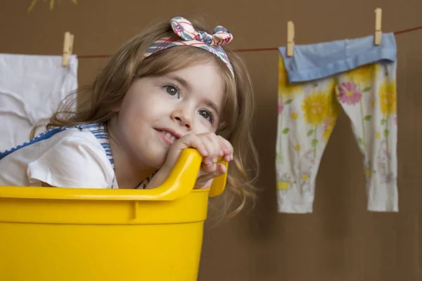 Niña bonita sonríe y se sienta en un baño amarillo. Un niño sueña con convertirse en adulto — Foto de Stock