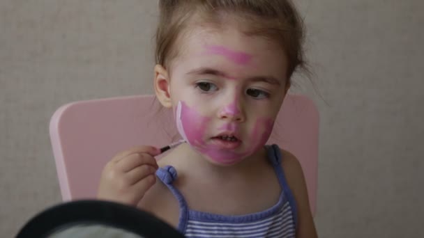 Biondo tre anni bambino pittura strisce di colore sul suo viso guardando specchio — Video Stock