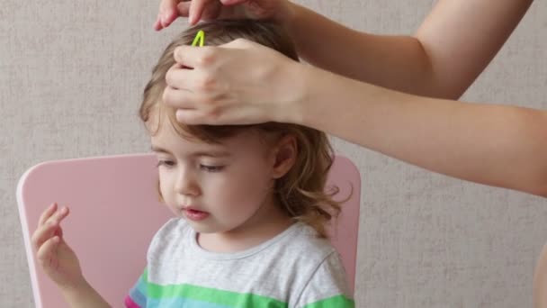 Женщина расчесывает дочке волосы дома. Концептуальная счастливая семья — стоковое видео