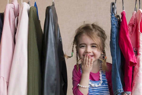 Adorable niña eligiendo ropa y sonriendo — Foto de Stock