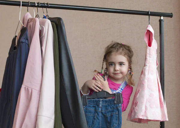 Adorable niña eligiendo ropa y sonriendo — Foto de Stock