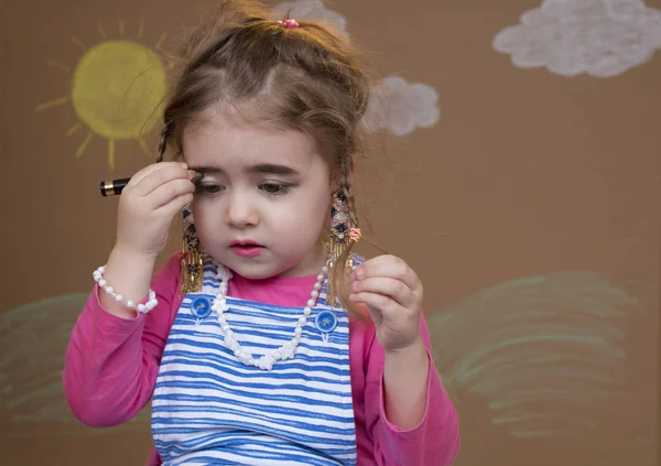 Little girl holding an eyebrow pencil in her hand. — Stock Photo, Image
