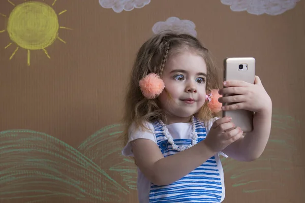Retrato emocional linda chica hace selfie con un teléfono celular. Adorable niño sonriente tomando una foto selfie con teléfono inteligente — Foto de Stock
