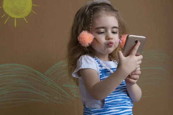 Retrato emocional linda chica hace selfie con un teléfono celular. Adorable niño sonriente tomando una foto selfie con teléfono inteligente — Foto de Stock