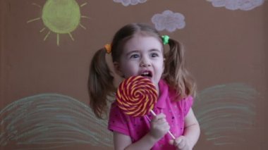 duygusal büyük şeker lolipop kızla portresi, çocuk yemek tatlılar. Lolipop güzel küçük kız